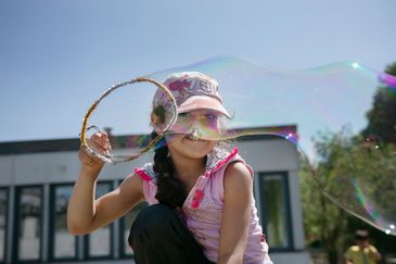 En flicka skapar en väldigt stor såpbubbla på en skolgård.