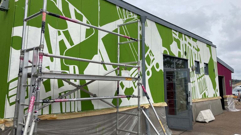 Bild på Omställningslabbets huvudbyggnad med byggställning. Byggnaden är målad i grönt med vita mönster.