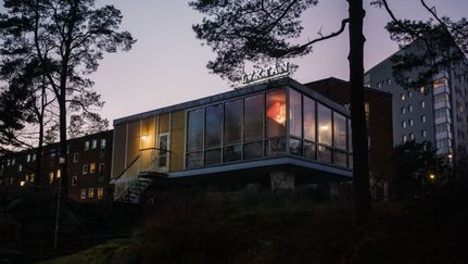 Bild på kulturföreningen Lyktan i skymningen, genom mörkret lyser lampor i fönstren på Lyktan.