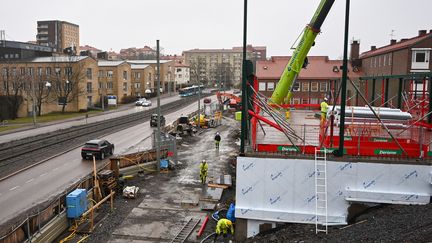 Stommen av en byggnad och en stor byggkran precis bredvid bilväg och spårvagnsspår.