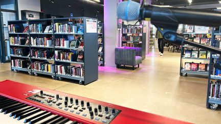 Foto på ett digitalt piano och en mikrofon i biblioteksmiljö.