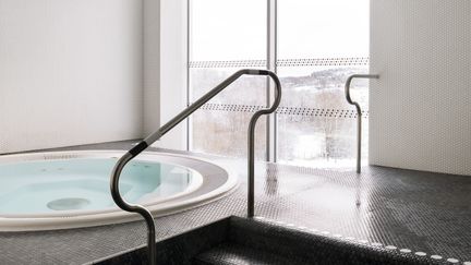 Bubbelpool vid stort fönster. I förgrunden syns en trappa med ledstång.