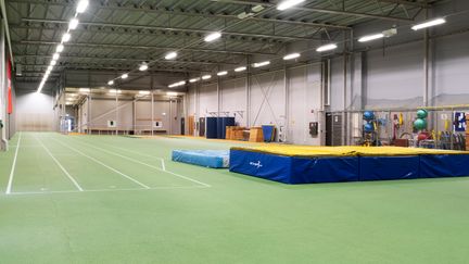 Stor idrottshall med grönt golv och bland annat tjockmatta