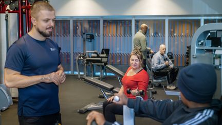 fem personer som tränar på olika stationer på gymmet