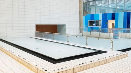 Barnbassängen och plaskbassängen i Angered Arena med vitt kakel och en vägg som är randig i olika blåa nyanser till höger i bild.