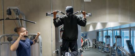 Ung person tränar på gym med instruktör.