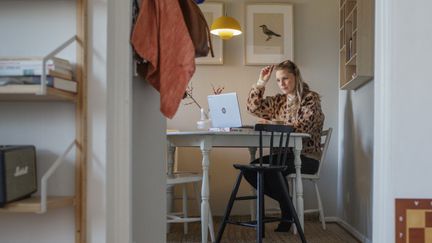 Person sitter vid ett köksbord i hemmamiljö och arbetar