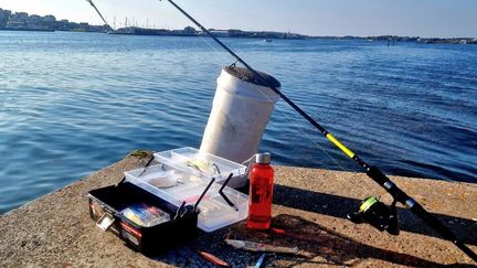 Fiskeutrustning på kajen och havet i bakgrunden.