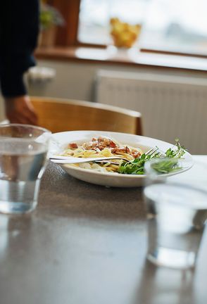 En tallrik mat och två vattenglas på ett bord i en skolmatsal. 