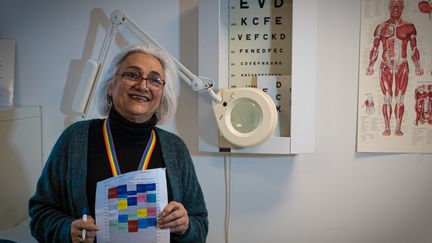 Mahbobeh ler mot kameran och håller upp ett schema.