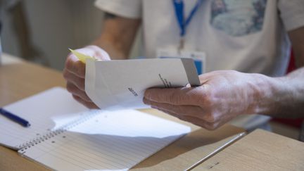 Händer som bläddrar bland valsedlar.