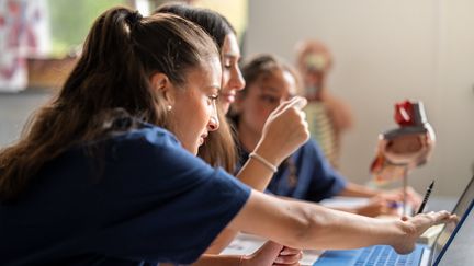 Elever som arbetar tillsammans vid datorn i klassrumsmiljö.