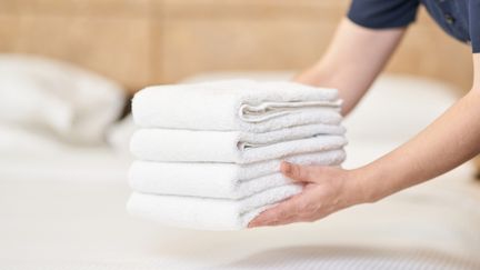 En person lägger handdukar på en säng.