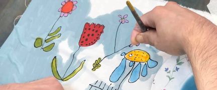 En person arbetar med att måla på tyg.