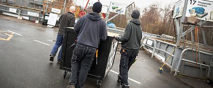 Tre personer går med vagn på återvinnigscentral.