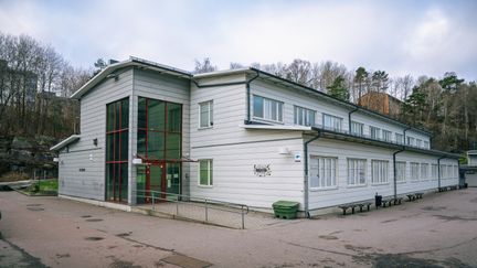 En stor vit skolbyggnad med en röd entré.