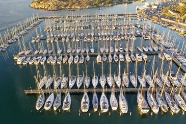 Hamn med segelbåtar och motorbåtar som ligger förtöjda vid bryggor. 