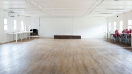 Stort rum med vita väggar och trägolv.