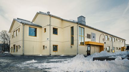 En överblick av Bergumsskolan med ett träd och några snöhögar i bakgrunden.