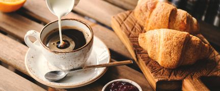 En kopp kaffe och två bröd på en bricka.