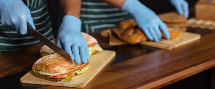 Två personer med handskar gör smörgåsar.
