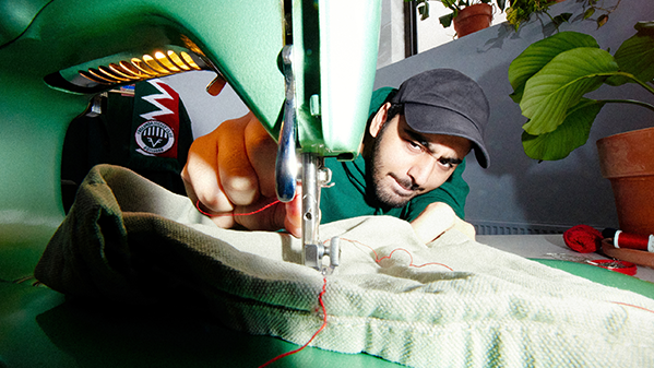 En man i keps trär en tråd på en symaskin