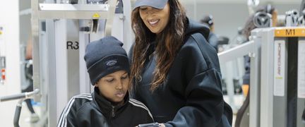 En ung kvinna står intill en yngre pojke och ler och visar något på mobilen