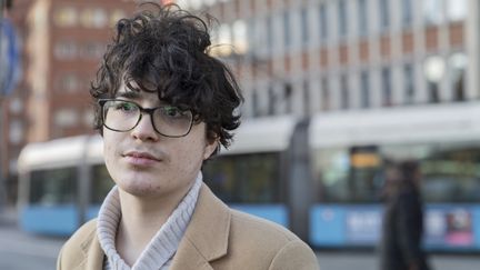 En ung kille står och tittar fram med en spårvagn bakom