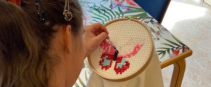 En person broderar en fjäril.