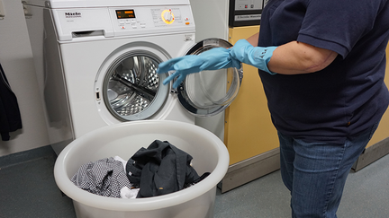 En person lägger in tvätt i en tvättmaskin.