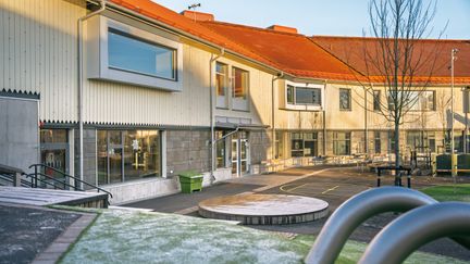Askimsskolans skolgård med några bänkar och ett träd i bakgrunden.