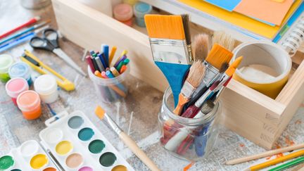 Ett bord med penslar, färger och pysselgrejer. 