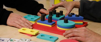 Två personer lägger färgade skivor på rätt platser i ett spel.