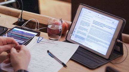 Detaljbild på en ipad, ett papper och en penna.