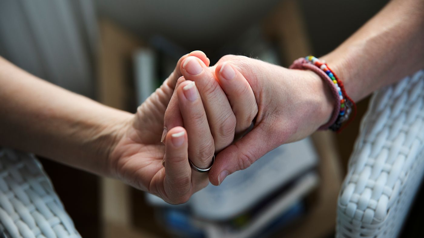 Detaljbild på två personer som håller hand.