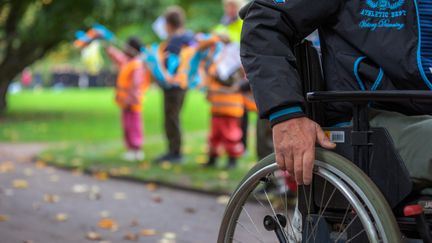  Ett foto av barn som står och hejar på passerande med rullstol