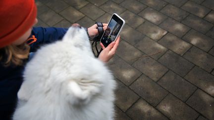 Ett barn tar en selfie med mobilkameran på sig och en vit hund.
