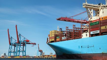 Ett foto av containrar lastade på ett stort ljusblått fartyg.