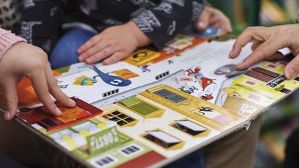 Barn och vuxenhänder bläddrar bland flikar i en uppslagen barnbok.