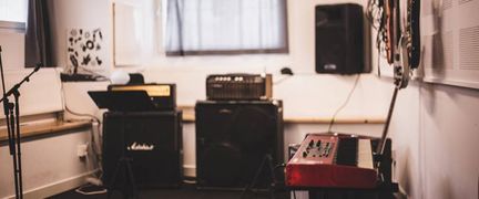 En rum med musikinstrument, mikrofonstativ och två förstärkare