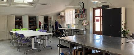 En rum med takfönster och glasdörr. I rummet finns tre olika bord med stolar placerade runt omkring.