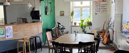 Ett runt matbord med 6 stolar runt bordet. i bild finns också en bardisk i trä med några pallar framför.