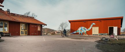 Brännöskolans skolgård med en skulptur och en person som cyklar i bakgrunden.
