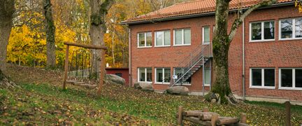 En röd tegelbyggnad med en gungställning av trä framför.