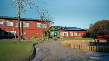 En väg som leder mot Älvegårdsskolan med skolans byggnader och en sandlåda i bakgrunden.