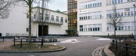 Sannaskolans skolgård med några bänkar och träd i bakgrunden.