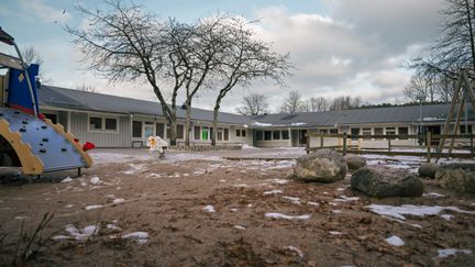 En skolgård med en rutschkana framför skolbyggnaden.