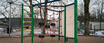 En skolgård med en klätterställning i en sandlåda.