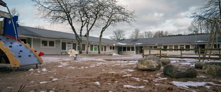 En skolgård med en rutschkana framför skolbyggnaden.