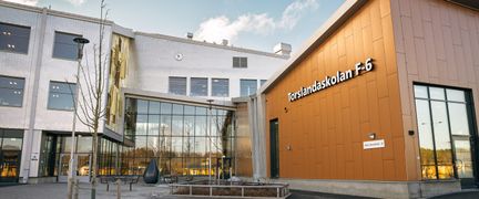 En skolbyggnad med texten Torslandaskolan F-6 på fasaden och en glasad entré